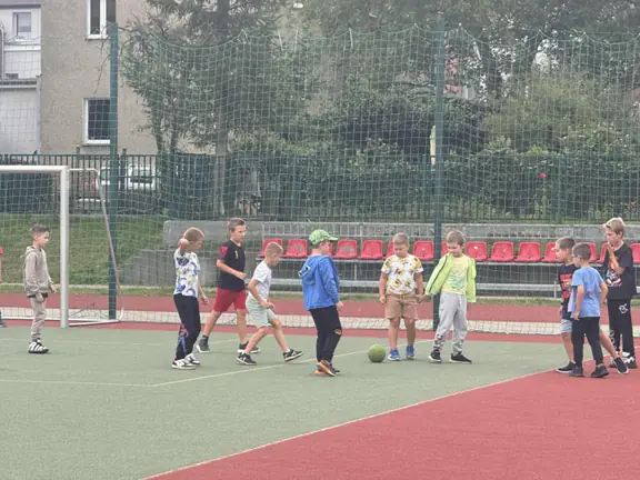 Uczniowie grają w piłkę nożną na boisku szkolnym