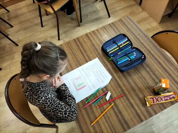 Dziewczynka wyszukuje w diagramie nazwy warzyw z wiersza -Na straganie.