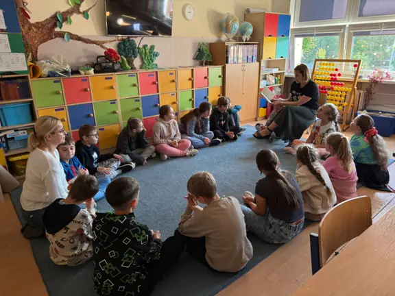 Wychowawczyni kl. IIIb czyta uczniom na dywanie.