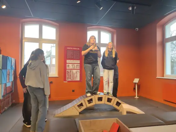 Uczennice pozują do zdjęcia stojąc na zbudowanym moście