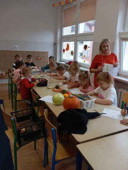 Nauczyciel uważnie obserwuje prace dzieci, gotowy pomóc im w każdej chwili