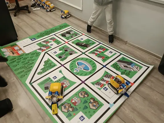 uczniowie sterują robotami SkriBot na specjalnej macie