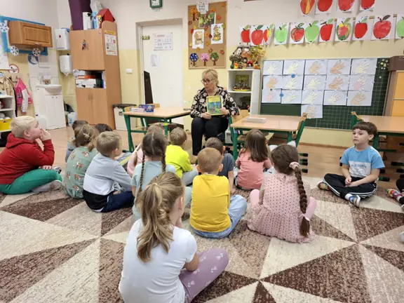 Pani bibliotekarka prezentuje przedszkolakom książeczkę o żółwiku Franklinie.