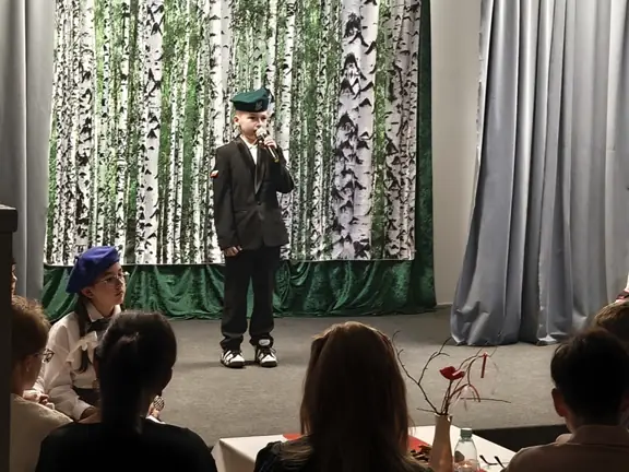 Uczeń w stroju żołnierza śpiewający na scenie