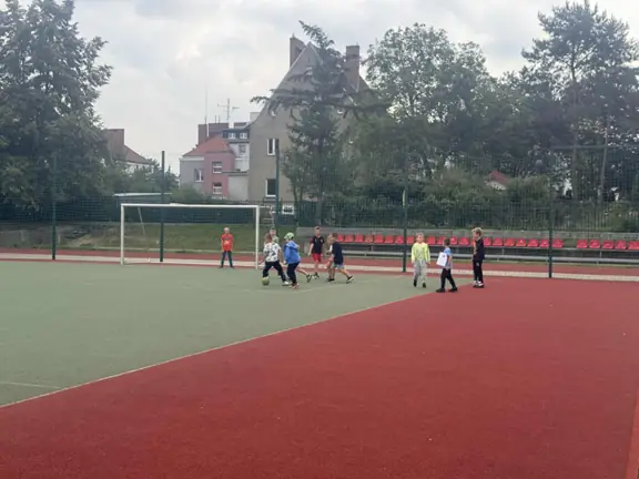 Uczniowie grają w piłkę nożną na boisku szkolnym