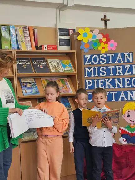 Uczeń kl. Ib czyta fragment bajki, jego koleżanka z klasy prezentuje klasową książeczkę.