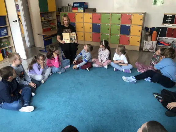 Nauczycielka czyta uczniom w klasie książkę