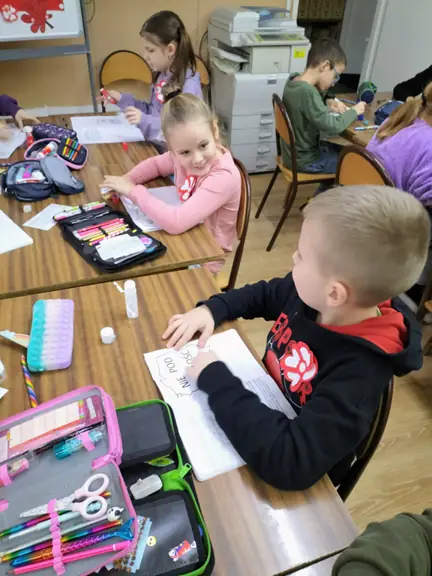 Dzieci wklejają mapę Polski do zeszytów.