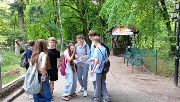 Grupa uczniów rozwiązuje zadania z gry terenowej