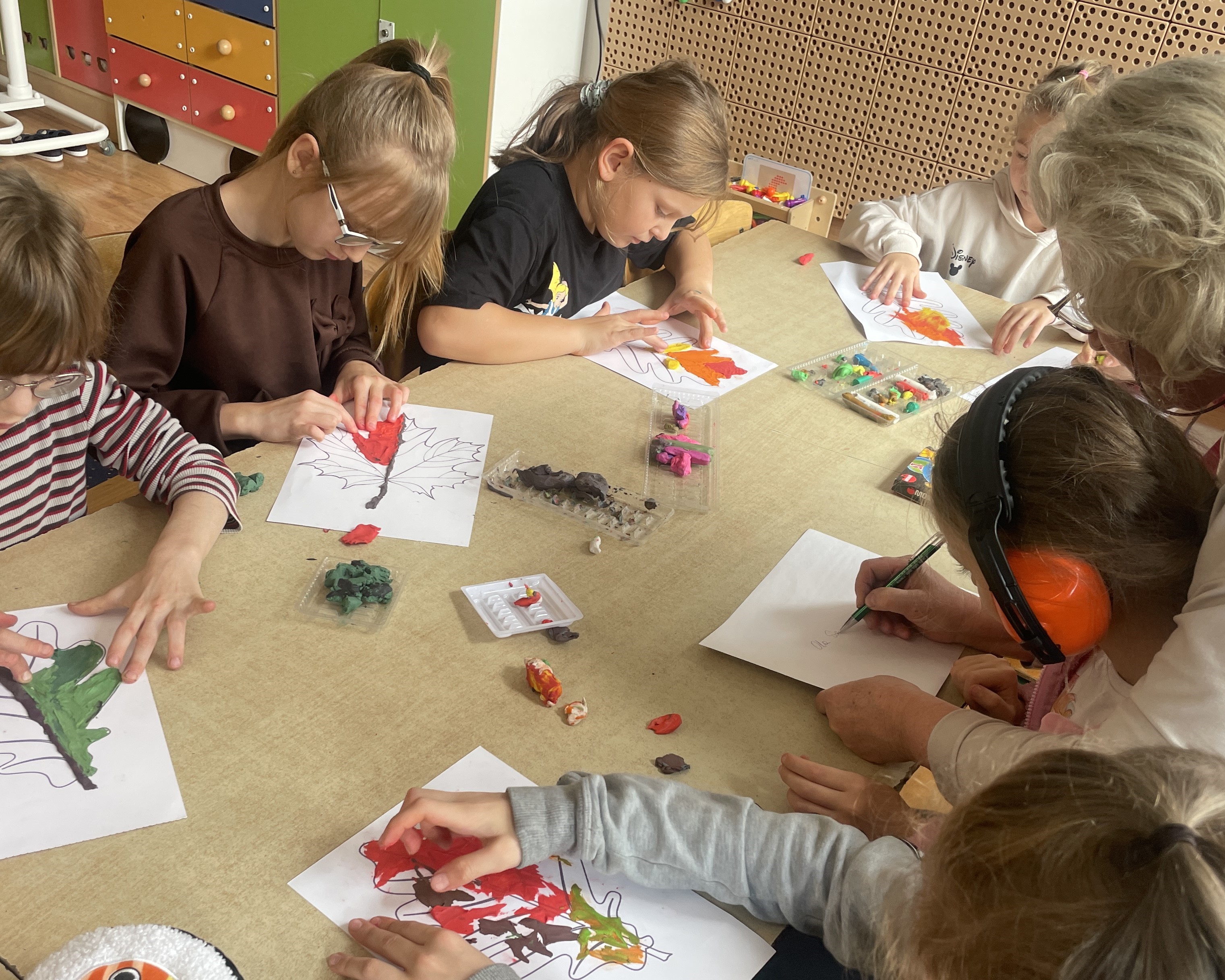 Wychowankowie świetlicy szkolnej kolorują listki metodą rozcierania plasteliny