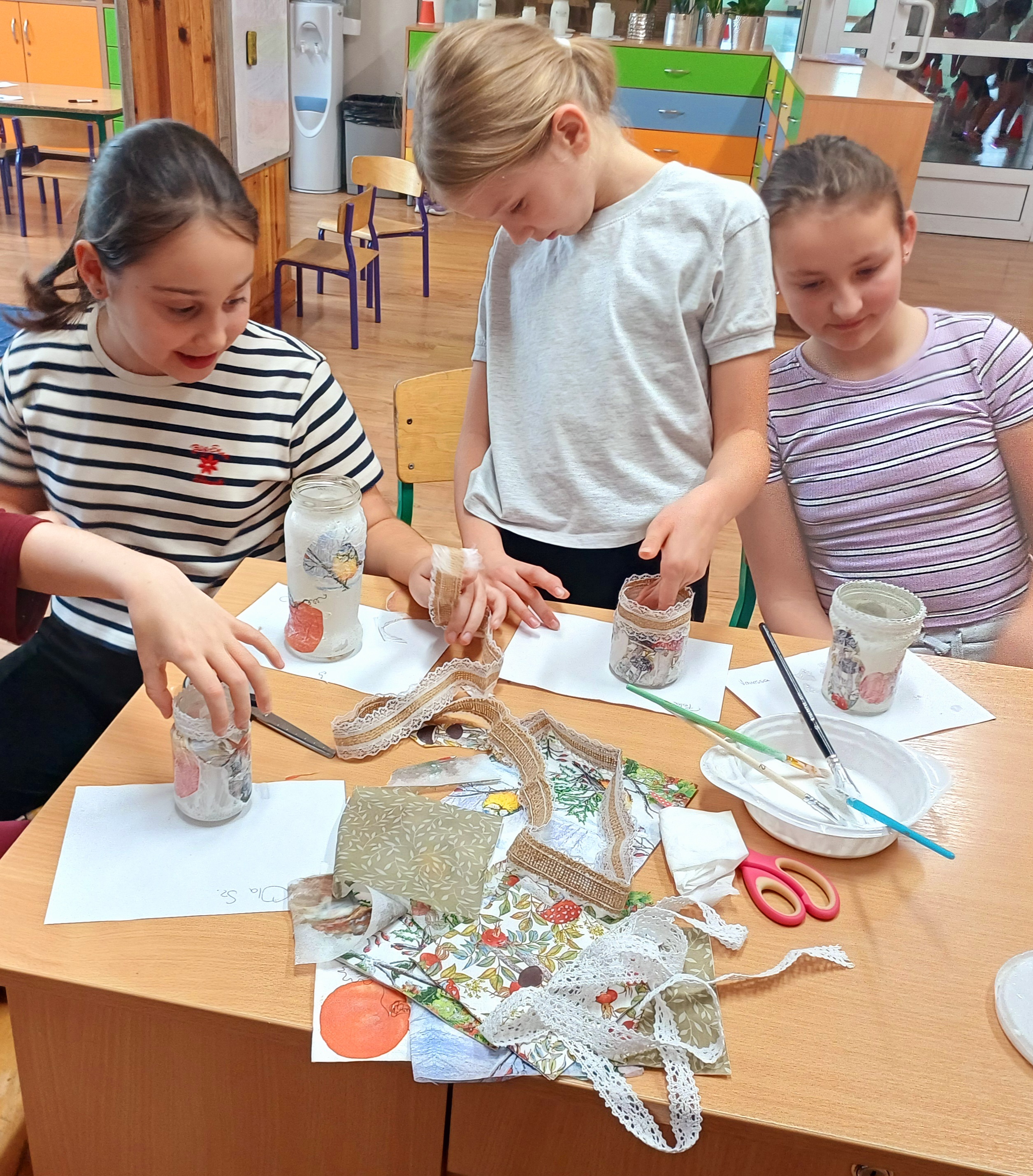 Uczennice dekorują lampiony koronkową taśmą