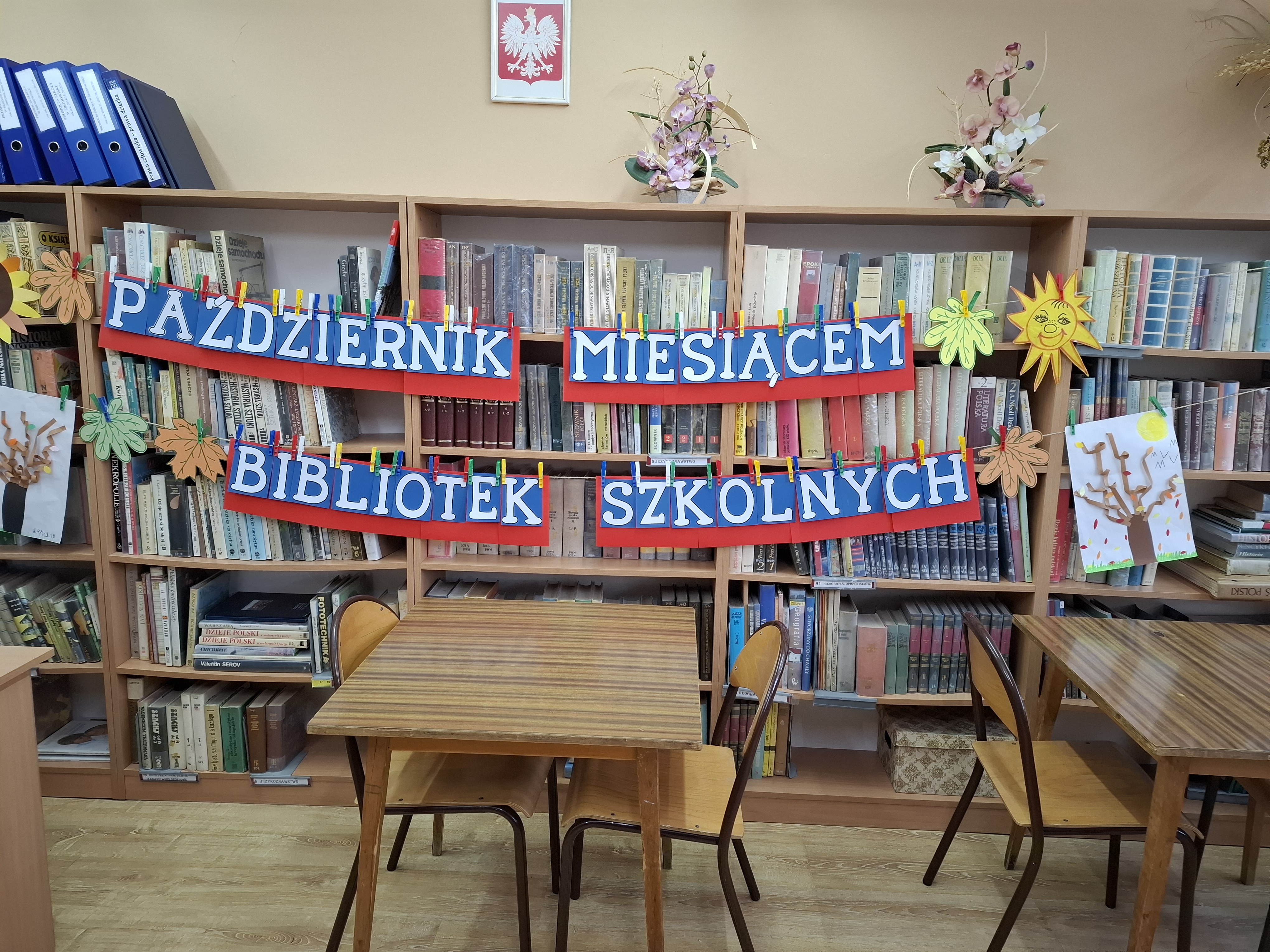 Zdjęcie czytelni w szkolnej bibliotece, gdzie jest girlanda z napisem- październik miesiącem bibliotek szkolnych.