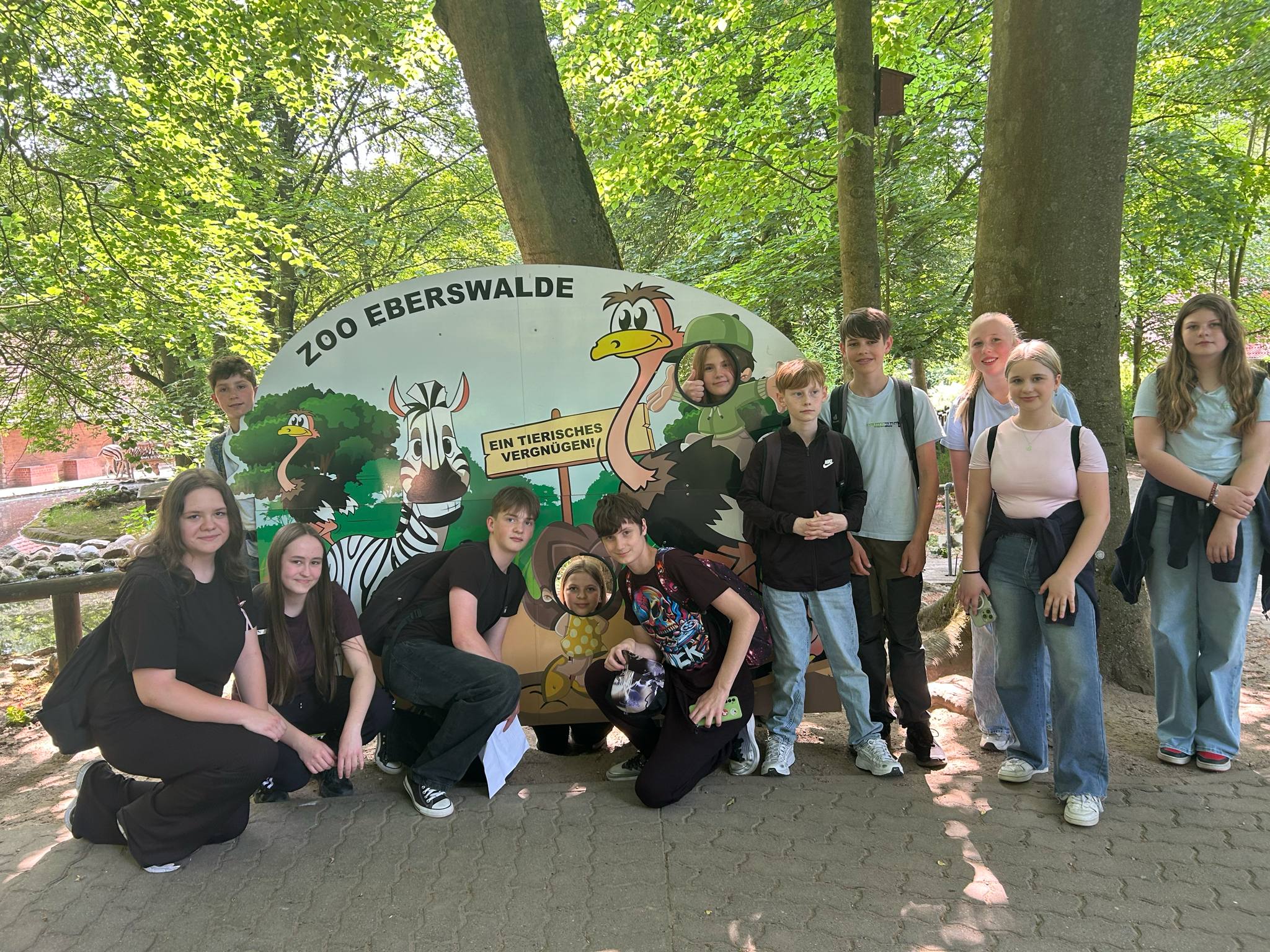 Grupa uczniów pozuje przy banerze Zoo