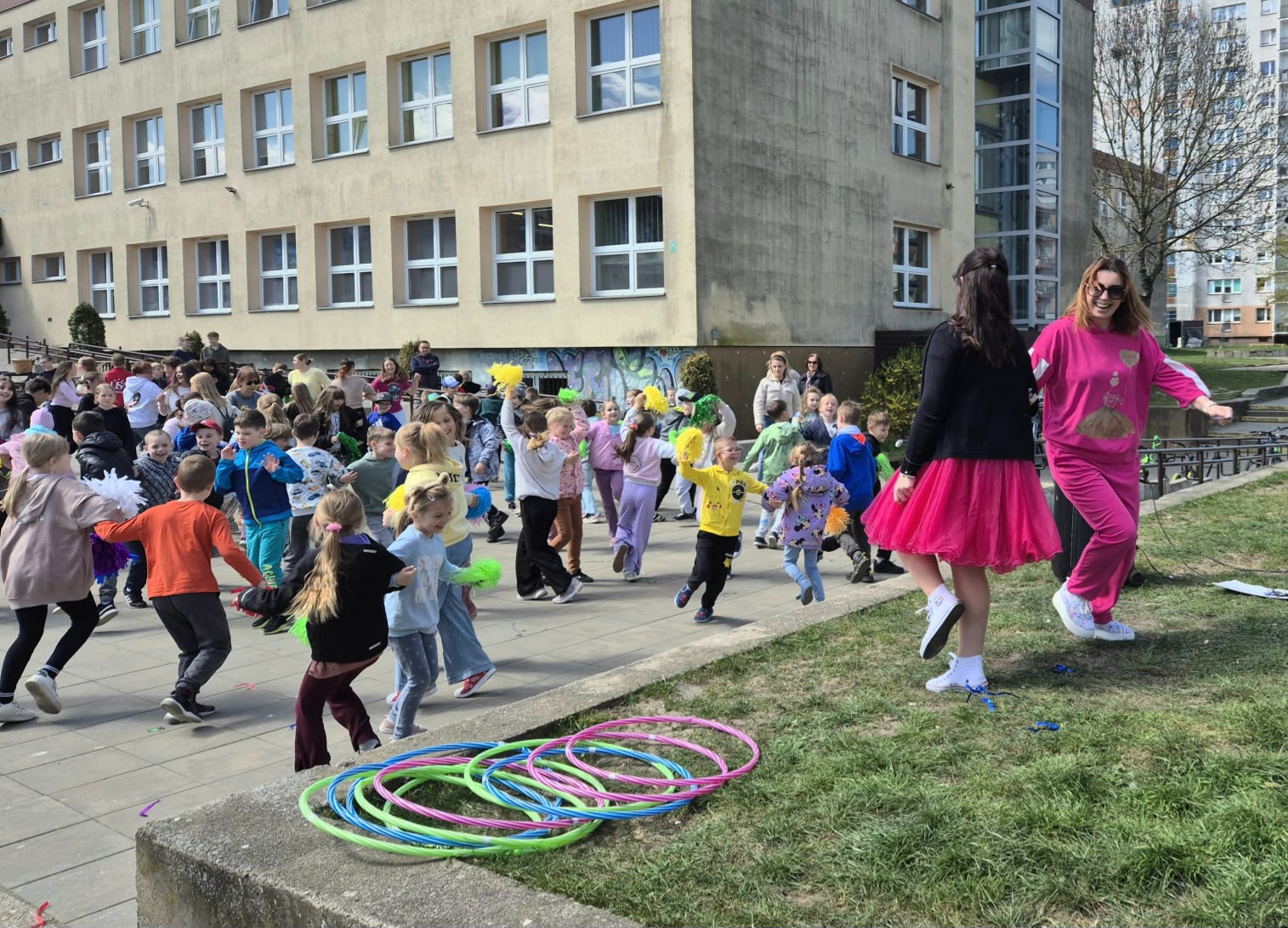 nauczyciele i uczniowie tańczą przez szkołą